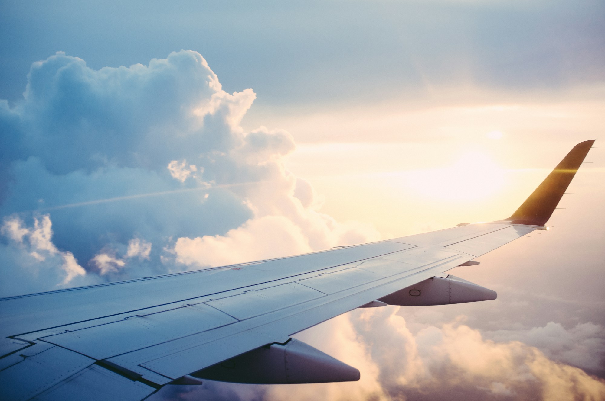 An aircraft wing above a sunlit sea of clouds